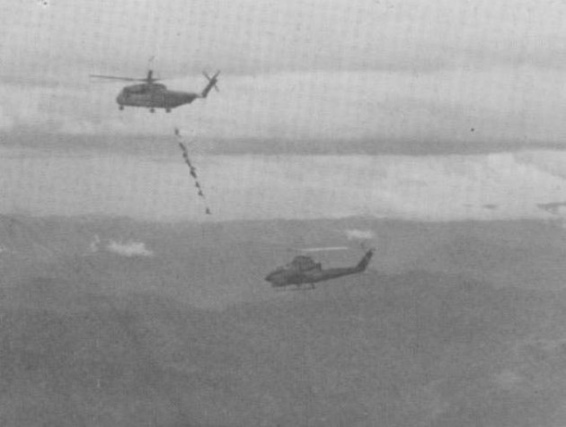 An HMH-463 heavy-lift Marine Corps helicopter, YH-20, heads east with Marine crew members, Green Beret Medics SSG John "Doc" Padgett and Sgt. John Browne after a CH-53D had a crash landed due to enemy gun fire and a B-40 rocket hitting it. A Marine Corps Cobra gunship from HML-367 Scarface is escorting the big chopper. (Photo courtesy of Joe Driscoll)