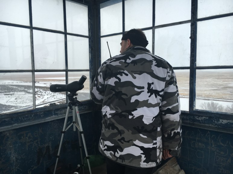 An occupier communicates via a handheld radio while on overwatch from a tower located on the property. SOFREP photo, all rights reserved.