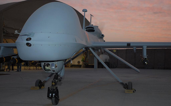 An MQ-1C Gray Eagle armed with Hellfire missiles revs up before taking flight at Camp Taji, Iraq.