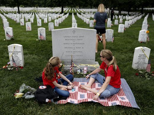 Leslie Hufstedler-Alverez and her daughter Grace Hufstedler sit at the grave of Lt Doyle Hufstedler at Arlington National Cemetery