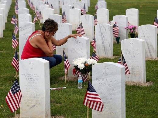 Maria Hiteshew kneels beside the grave of her husband Barry Hiteshew