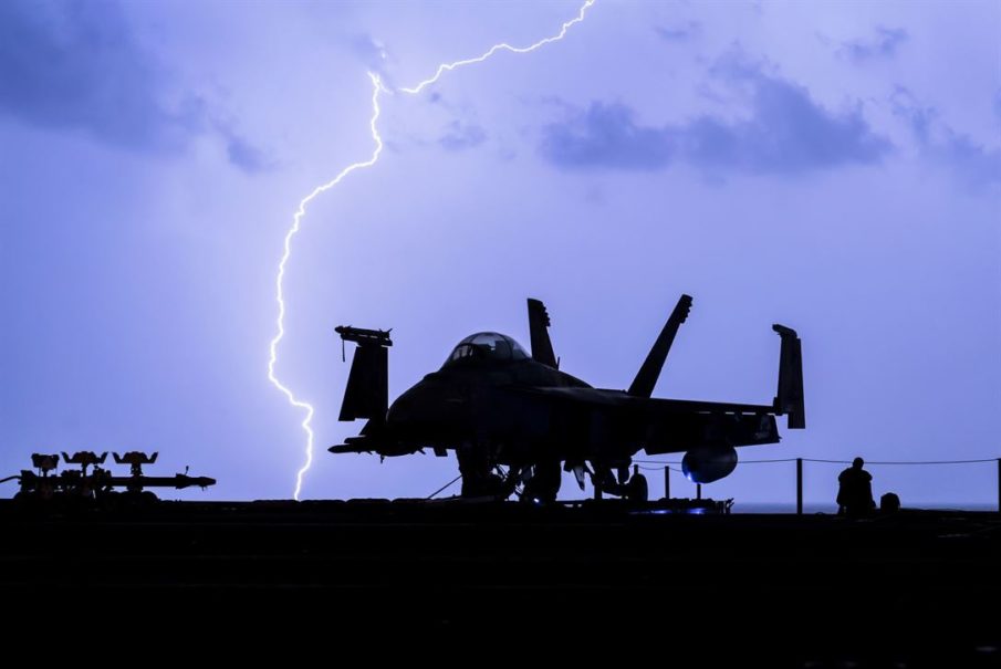Lightning strikes near an F-18 Hornet on the USS Theodore Roosevelt