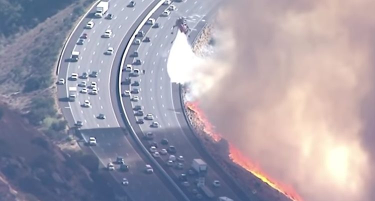 Watch: Firefighting helicopters try to douse flames alongside evacuating cars in California