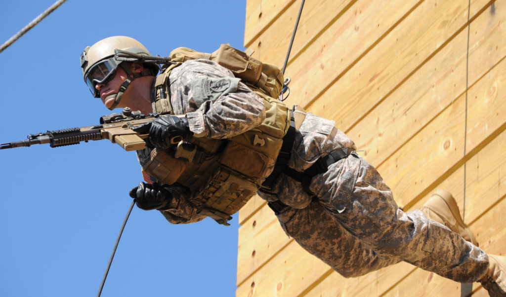 A 7th Special Forces Group (Airborne) Green Beret rappels with his weapon from a 60-foot tower at Eglin Air Force Base.
