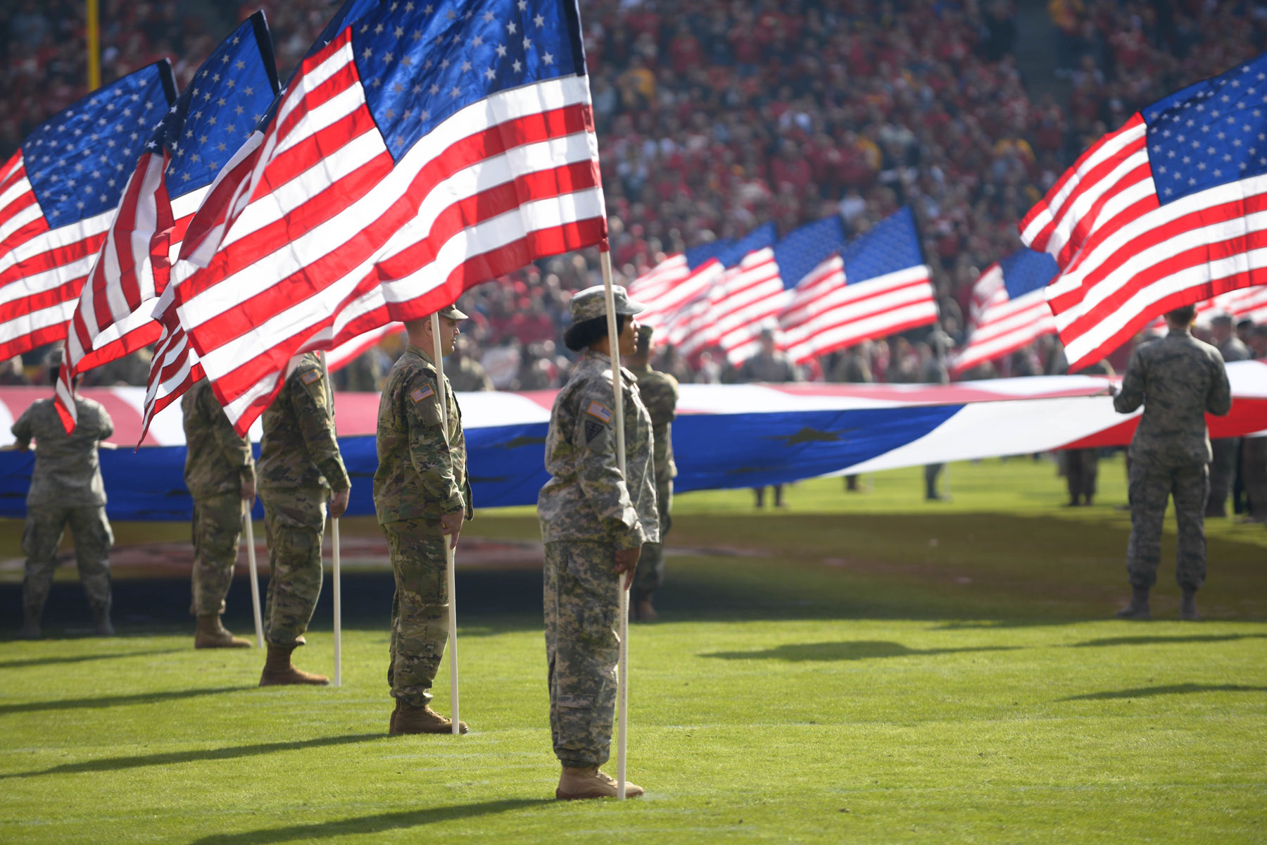 American soldiers carrying flags in stadium