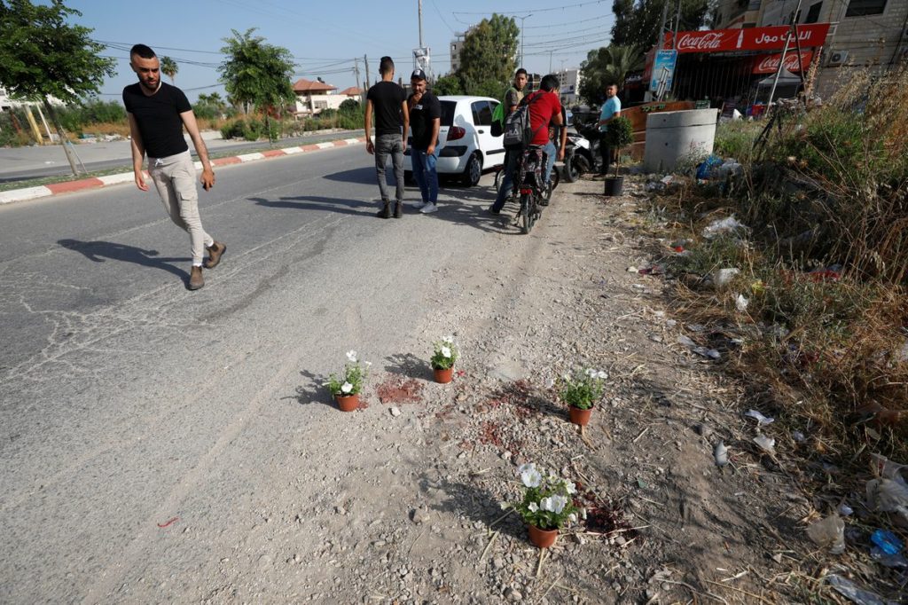 Palestinians from the West Bank town of Jenin walk by the shootout location where members of Islamic Jihad were killed and arrested by Israeli forces.