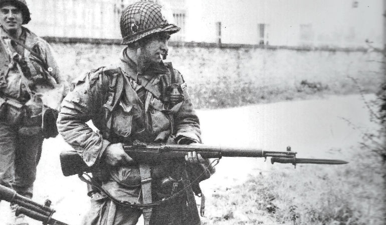 A U.S. paratrooper guards German prisoners with an M1 Garand on D-Day
