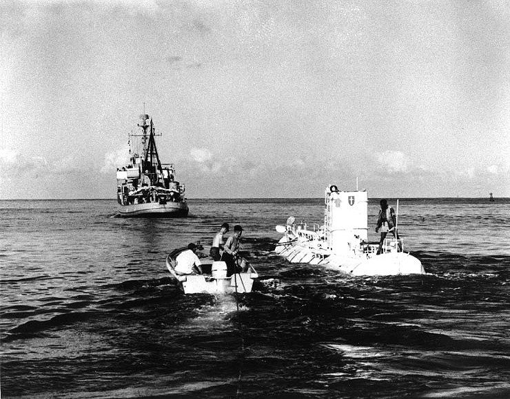 Jacques Piccard, co-designer of the bathyscaphe, and his assistants make final checks aboard her, prior to Trieste's first deep dive in the Marianas Trench. On 15 November 1959 (Wikimedia Commons). Source: https://commons.wikimedia.org/wiki/File:Bathyscaphe_Trieste_beforedive.jpg
