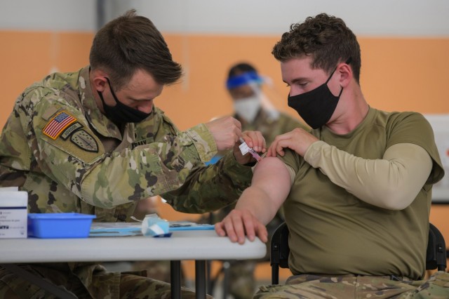U.S. Army Staff Sgt. Paul Kovari, left, a medic with 2nd Cavalry Regiment, administers a COVID-19 vaccination to a fellow Soldier at the 7th Army Training Command's (7ATC) Rose Barracks, Vilseck, Germany, May 3, 2021 (US Army). Source: https://www.army.mil/article/246190/army_medicine_europe_makes_steady_progress_in_covid_19_vaccine_distribution 