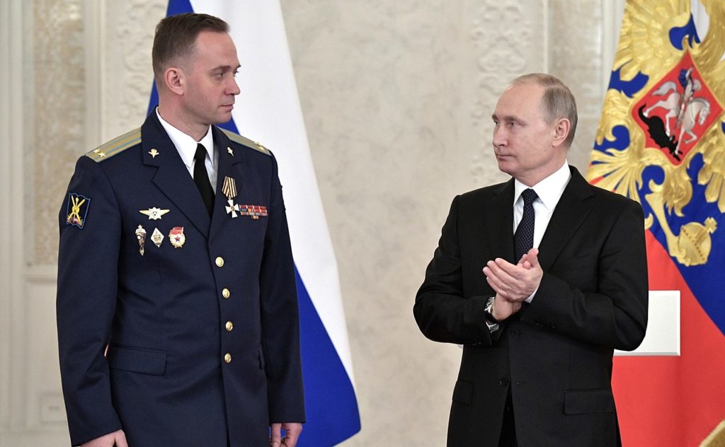 Meeting of Russian President Vladimir Putin with a servicemen who participated in the antiterrorist operation in Syria. Lieutenant Colonel Denis Kletyonkin was awarded the Order of St. George IV degree (Kremlin.ru, CC BY 4.0 , via Wikimedia Commons). Source: https://commons.wikimedia.org/wiki/File:Vladimir_Putin_with_military_people_(2017-12-28)_14.jpg