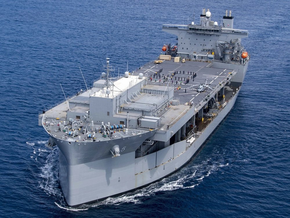 Sailors assigned to expeditionary sea base USS Miguel Keith (ESB 5) stand in formation on the flight deck as the ship sails in the Pacific Ocean, Aug 19. Miguel Keith is underway conducting routine operations in U.S. 3rd Fleet. (DVIDS, U.S. Navy photo by Mass Communication Specialist 2nd Class Hector Carrera). Source: https://www.dvidshub.net/image/6798661/uss-miguel-keith-photoex