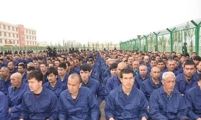 Detainees in a Xinjiang Re-education Camp located in Lop County listening to "de-radicalization" talks (Wikimedia Commons). Source: https://en.wikipedia.org/wiki/File:Xinjiang_Re-education_Camp_Lop_County.jpg