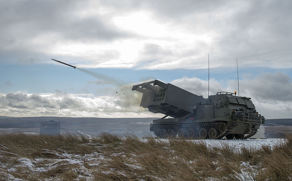 MLRS captured as a training round leaves the launch tube on the ranges at Otterburn. Gunners from Army Reserve unit 101 (Northumbrian) Regiment Royal Artillery and 1 Regiment Royal Horse Artillery (1 RHA) exercising in Otterburn Ranges in the North of England. The soldiers have been firing the Multi Launch Rocket System (MLRS) on the ranges to hone their skills and maintain combat effectiveness (Cpl Jamie Peters RLC, OGL v1.0OGL v1.0, via Wikimedia Commons). Source: https://commons.wikimedia.org/wiki/File:MLRS_captured_as_a_training_round_leaves_the_launch_tube_on_the_ranges_at_Otterburn._MOD_45158570.jpg