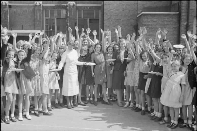 Aid From America- Lend-lease Food, London, England, 1941 A large group of smiling school children wave for the camera as they receive plates of bacon and eggs, imported from America as part of the Lend-Lease scheme. The headmistress of the school is in the centre. The photograph was taken in the playground of the school and was probably taken in late August or early September 1941 (Ministry of Information Photo Division Photographer, Public domain, via Wikimedia Commons). Source: https://commons.wikimedia.org/wiki/File:Aid_From_America-_Lend-lease_Food,_London,_England,_1941_D4324.jpg