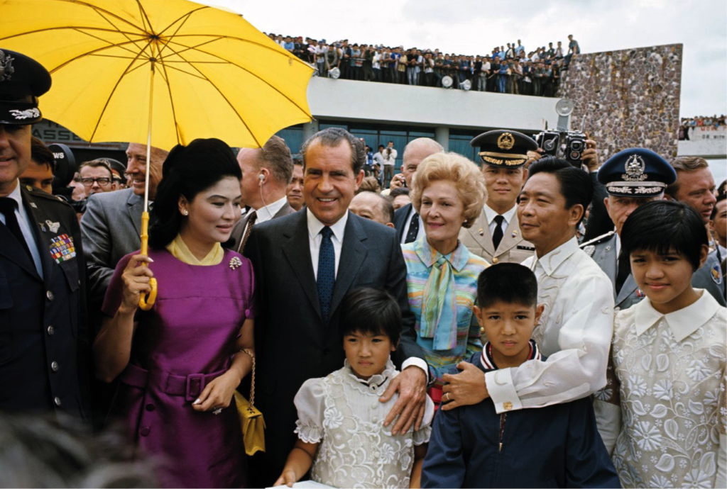 Former President Richard Nixon and Pat Nixon (center) at the Manila International Airport with Imelda and Ferdinand Marcos Sr. and their children Irene, Bongbong (Marcos Jr.), and Imee (White House Photo Office, Public domain, via Wikimedia Commons). Source: https://commons.wikimedia.org/wiki/File:Richard_Nixon_with_the_Marcos_family.png