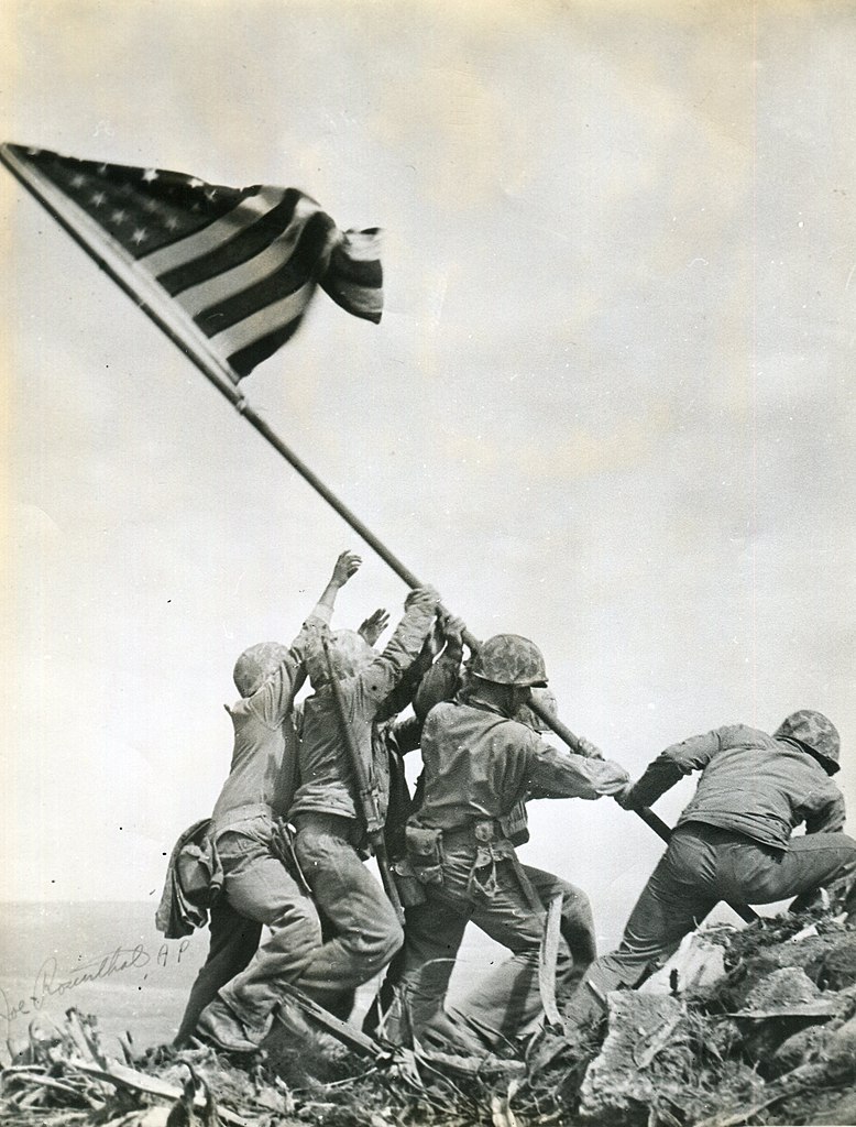 The famous Rosenthal photo of the flag going up on Iwo Jima (Archives Branch, USMC History Division, CC BY 2.0 <https://creativecommons.org/licenses/by/2.0>, via Wikimedia Commons).
