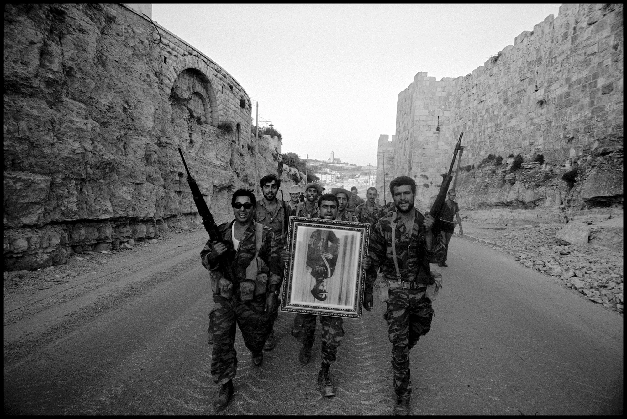Israeli soldiers, who captured the Old City from the Jordanians during the Six-Day War, carry a confiscated portrait of Jordan’s King Hussein through East Jerusalem, June, 1967.PHOTOGRAPH BY LEONARD FREED / MAGNUM