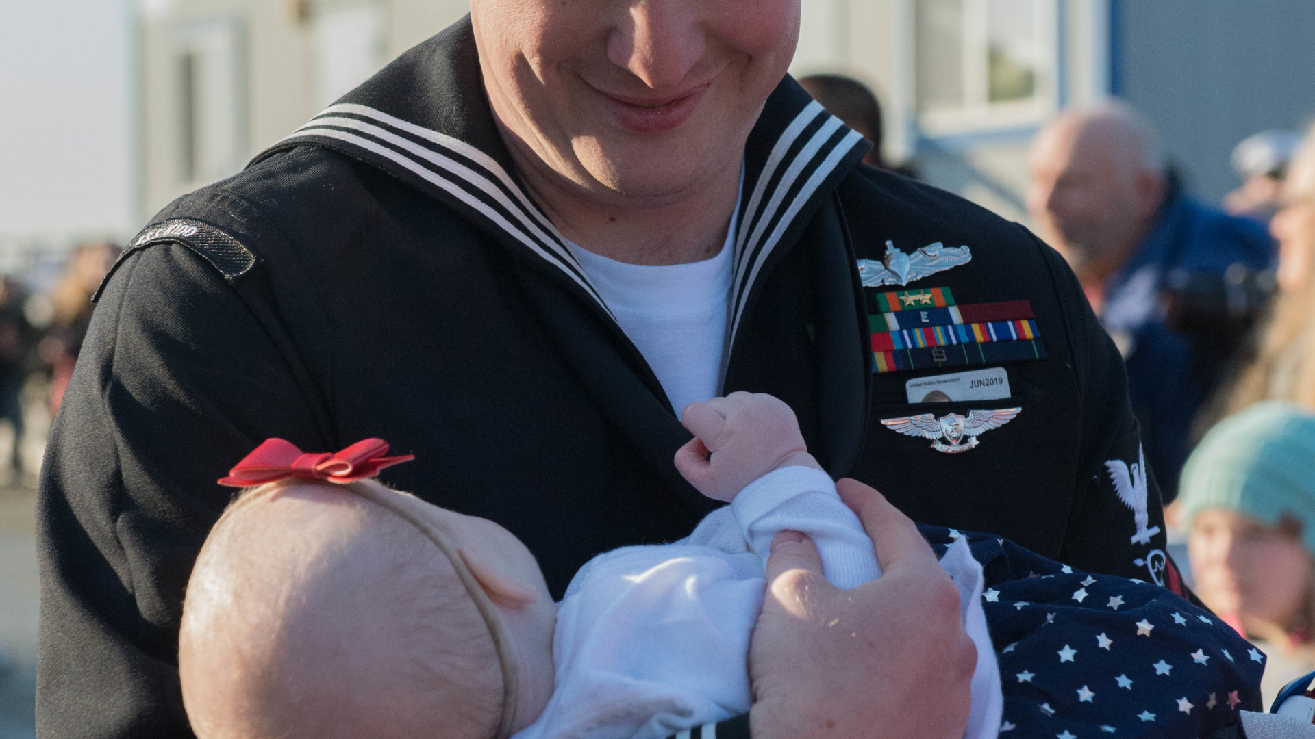 sailor holds baby during homecoming