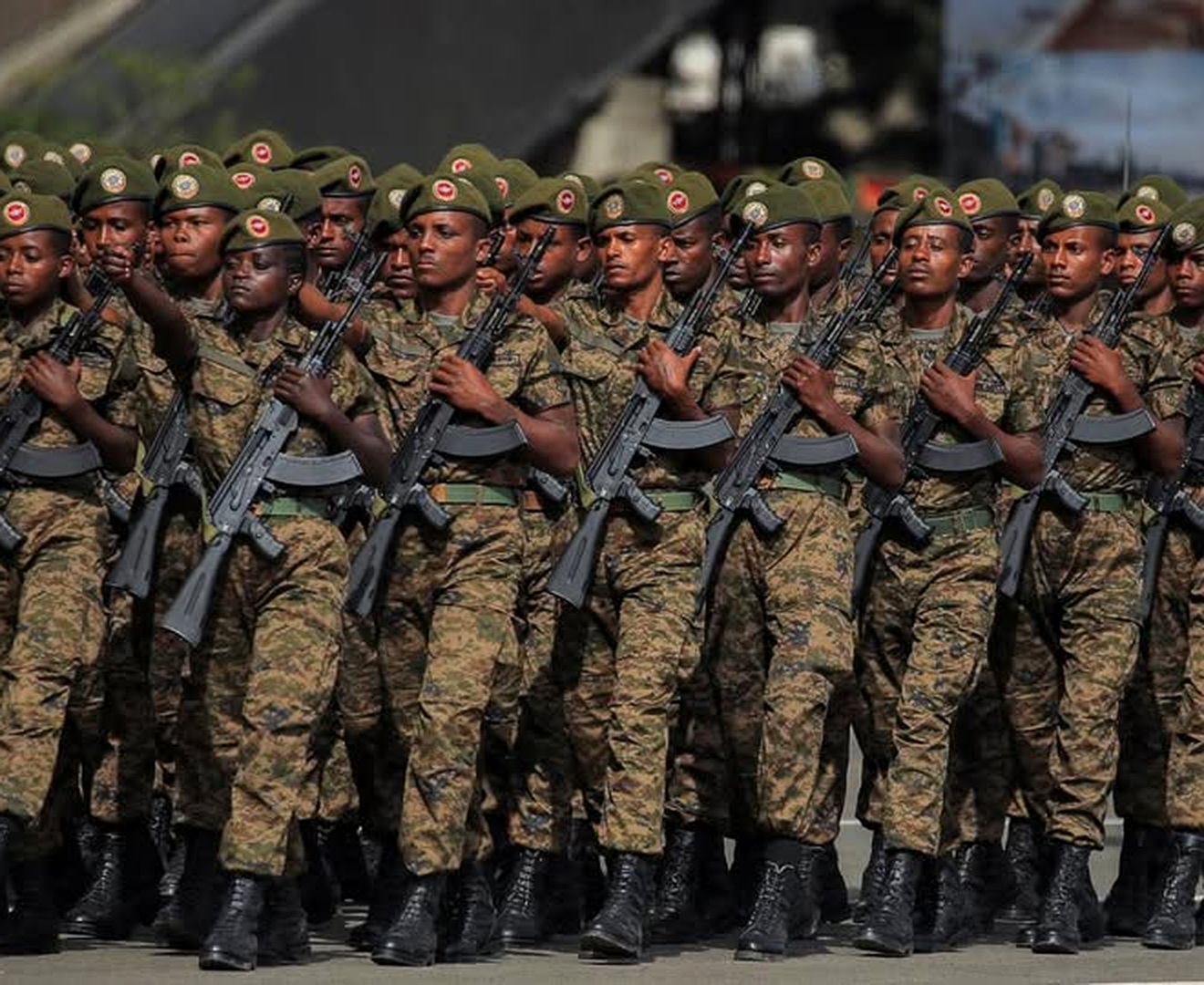 Ethiopian soldiers in camouflage uniforms march in formation while carrying rifles during a military parade.